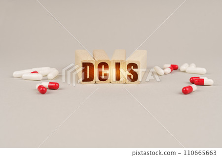On a gray surface are pills and a red wooden block with the inscription - DCIS 110665663