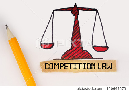 Next to the painted scales of justice lies a pencil and a strip of paper with the inscription - Competition Law Next to the painted scales of justice lies a pencil and a strip of paper with the inscription - Competition Law 110665673