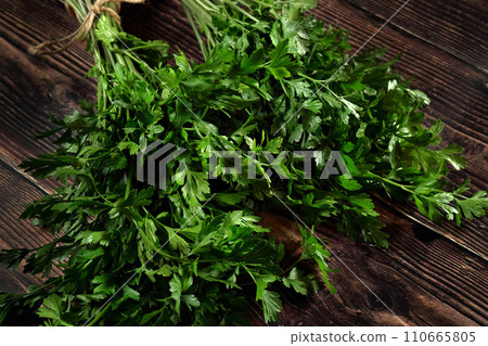 Green parsley leaves which are used as herb in kitchen, on dark wooden board Green parsley leaves which are used as herb in kitchen, on dark wooden board 110665805