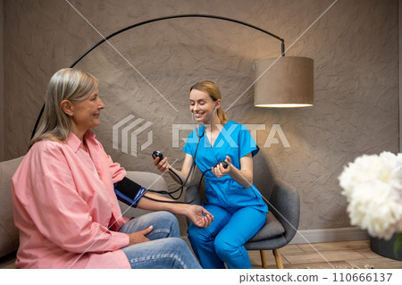 Nurse or doctor checking blood pressure to senior woman. 110666137