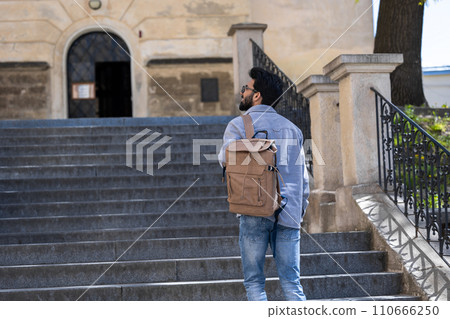 Young tall hindu man standing on the steps of an old building 110666250