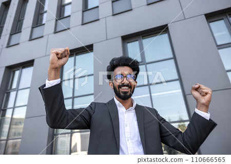 Waist up of an excited successful hindu businessman near the office building Waist up of an excited successful hindu businessman near the office building 110666565