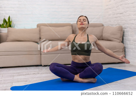Young woman sitting in a lotus pose and doing stretching Young woman sitting in a lotus pose and doing stretching 110666652