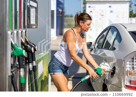 Woman filling up tank of her car with gasoline Woman filling up tank of her car with gasoline 110669992