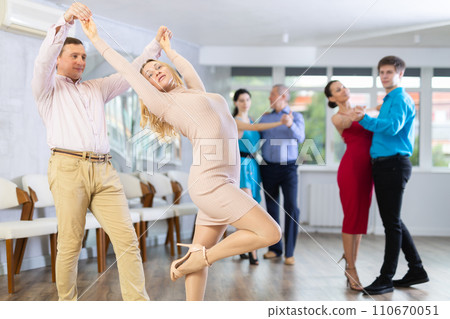 Dance training in dance studio - men and women of different ages learn dances from different eras Dance training in dance studio - men and women of different ages learn dances from different eras 110670051