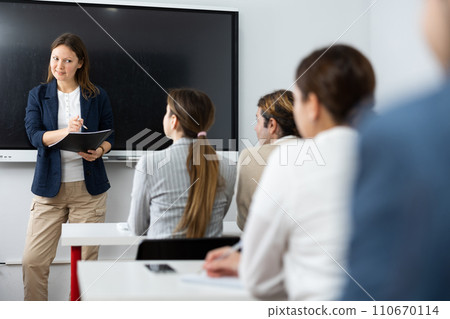 Positive successful woman near interactive board conducting business training for audience in classroom 110670114