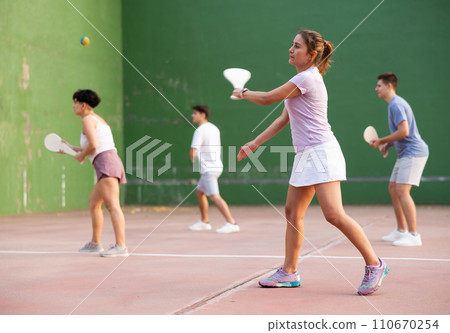 Sporty woman performing basic strokes during paleta fronton group training 110670254