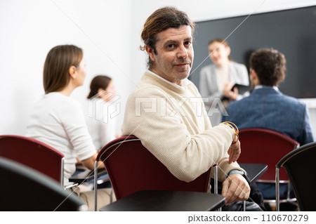 Positive middle-aged man turning around and looking at camera during advanced training course in auditory 110670279