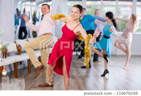 Happy brunette dancing jive with male partner during New Year party Happy brunette dancing jive with male partner during New Year party 110670298