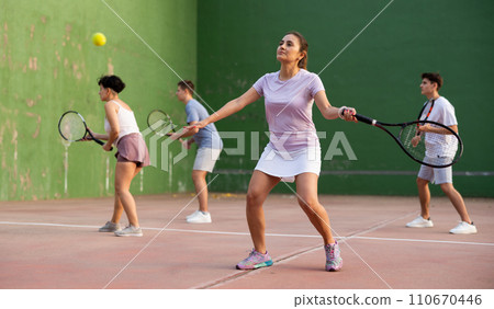 Sportive woman in shorts and t-shirt playing frontenis on court Sportive woman in shorts and t-shirt playing frontenis on court 110670446