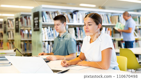 Female college student working on a project with a male student 110670498