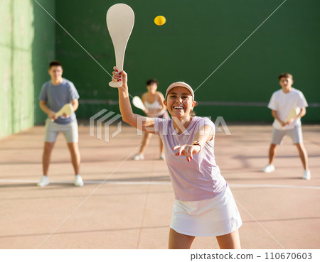 Portrait of sporty girl playing paleta fronton on outdoor court, ready to hit ball. Healthy and active lifestyle concept 110670603
