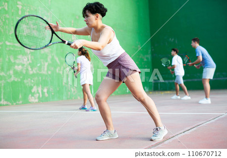 Woman serving ball during frontenis game outdoors Woman serving ball during frontenis game outdoors 110670712