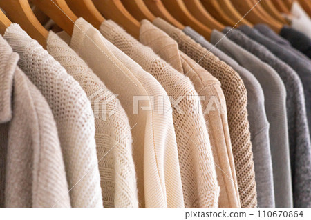 Hanger with neutral beige and white clothes on a white background. Hanger with neutral beige and white clothes on a white background. 110670864