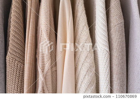 Hanger with neutral beige and white clothes on a white background. Hanger with neutral beige and white clothes on a white background. 110670869