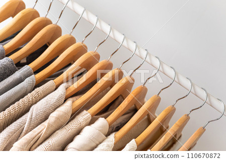 Hanger with beautiful neutral beige, white and gray clothes on a white background. Copy space. 110670872