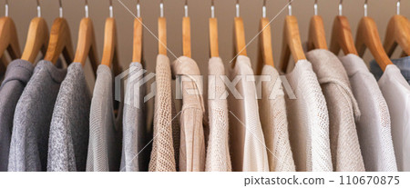 Hanger with neutral beige and white clothes on a white background. Hanger with neutral beige and white clothes on a white background. 110670875