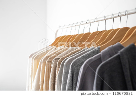 Hanger with neutral beige and white clothes on a white background. 110670881
