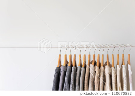 Hanger with neutral beige and white clothes on a white background. 110670882