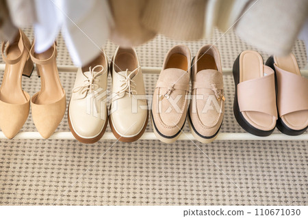 Women's seasonal autumn and spring shoes in the closet at home. Shoes and clothes in beige  110671030