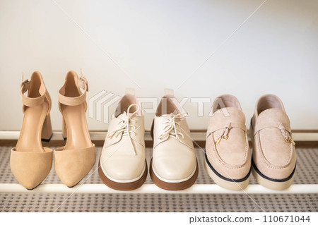 Women's seasonal autumn and spring shoes in the closet at home. Shoes and clothes in beige  110671044