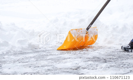 Man shoveling snow off of his driveway after a winter storm in Canada. Man with snow shovel cleans sidewalks in winter. Winter time. 110671123