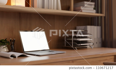 A laptop computer mockup and office supplies on a wooden desk in a modern office workspace. 110671217