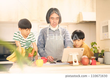 父子一邊煮飯一邊看著平板電腦 110671630