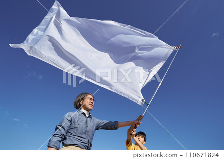 A man and a boy raising a flag under the blue sky 110671824
