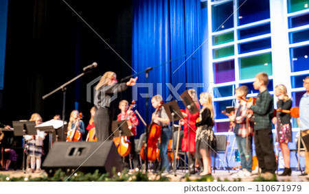 defocused elementary musical concert with children lined up on stage to sing. 110671979