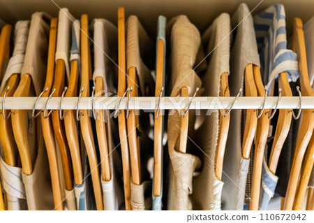 Hanger with beautiful neutral beige, white and gray clothes on a white background. View from above. 110672042