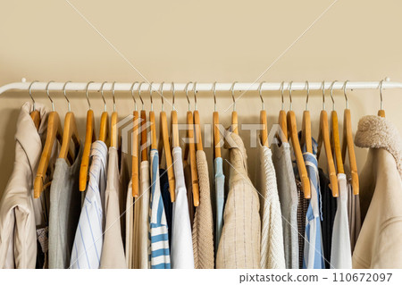 Hanger with neutral beige and white clothes on a white background. 110672097