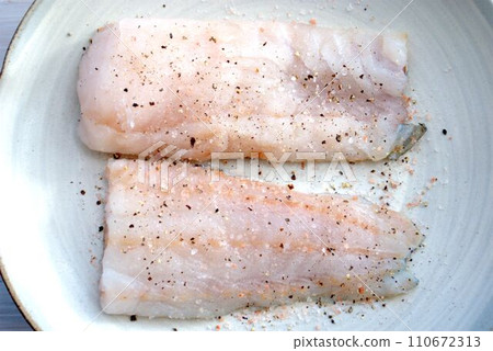 Raw cod fillets seasoned with salt and pepper Raw cod fillets seasoned with salt and pepper 110672313