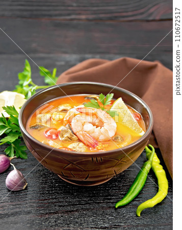 Soup Tom Yum with lemons in bowl on black wooden board 110672517