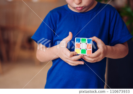 Thoughtful serious inquisitive boy try to complete the rubik's cube. Game childhood development 110673933
