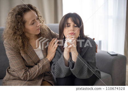 Female psychologist calm down woman patient with sad mental disorder crying upset sitting on couch 110674328