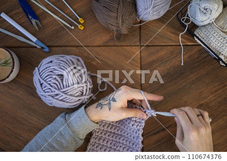Feminine male hands crochet handmade artwork hobby wooden table with sewing tools closeup top view Feminine male hands crochet handmade artwork hobby wooden table with sewing tools closeup top view 110674376