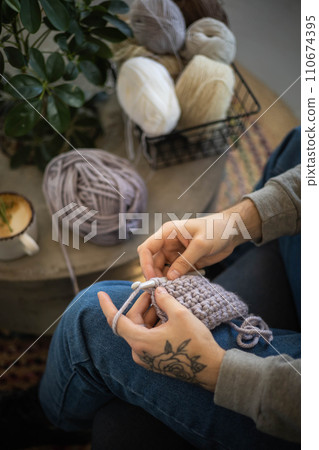 Male hands crochet handmade artwork use wool yarn and hook over table with coffee top view 110674395