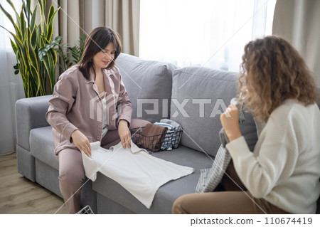 Woman space organizer couch teaching client neatly folding clothes storage method minimalism 110674419