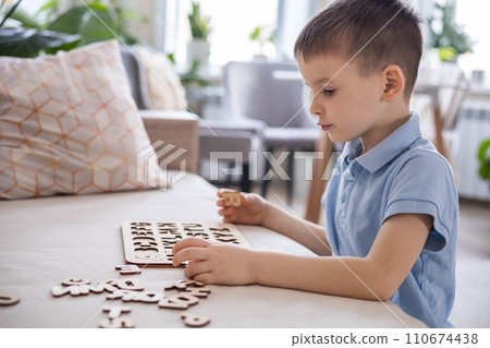 A Caucasian light-haired boy of five years old with blue eyes is putting together a puzzle A Caucasian light-haired boy of five years old with blue eyes is putting together a puzzle 110674438
