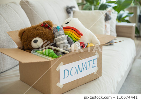 On the living room couch is a box full of toys for donation. On the living room couch is a box full of toys for donation. 110674441