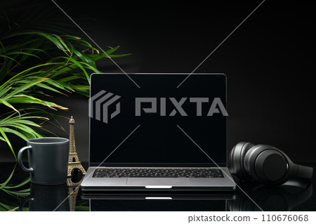 Laptop with black screen on working desk with cup and earphones on black background Laptop with black screen on working desk with cup and earphones on black background 110676068