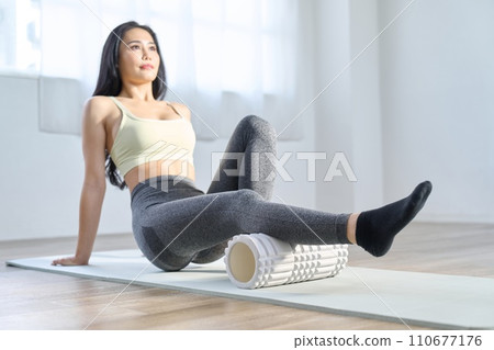 一位女士使用泡沫軸放鬆膝蓋後部 110677176