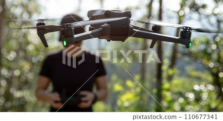 People remote control a flying drone in summer forest People remote control a flying drone in summer forest 110677341