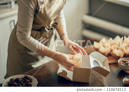 woman bakery shop owner holding delivery box for customer order. Bakery chef baking pastry and cake in the kitchen. Small business entrepreneur and food delivery concept. woman bakery shop owner holding delivery box for customer order. Bakery chef baking pastry and cake in the kitchen. Small business entrepreneur and food delivery concept. 110678513