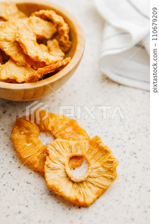 Dried pineapple rings on kitchen table. 110679209