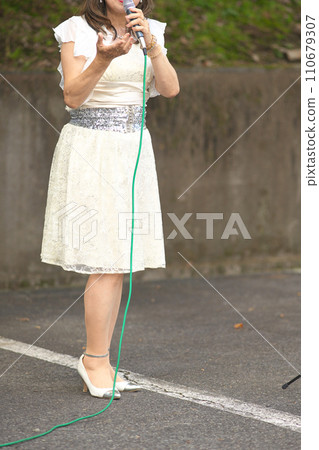 Woman singing at an outdoor event Woman singing at an outdoor event 110679307