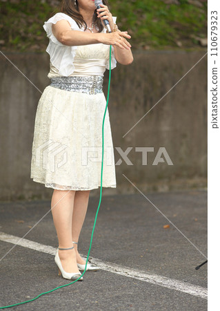 Woman singing at an outdoor event Woman singing at an outdoor event 110679323
