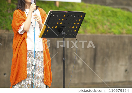 Woman singing at an outdoor event 110679334