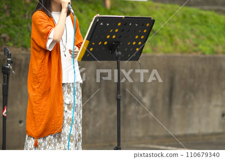 Woman singing at an outdoor event Woman singing at an outdoor event 110679340